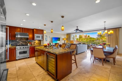 Fully equipped kitchen with stainless appliances and breakfast bar opens to the living space.