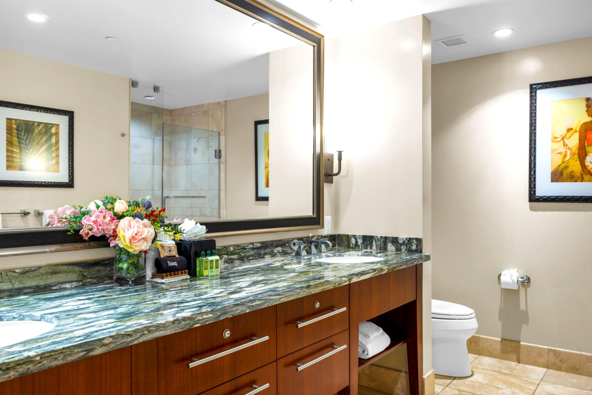 Your spacious primary bath features a granite dual vanity, walk-in shower, and soaking tub stocked with L’Occitane amenities. HKH-203