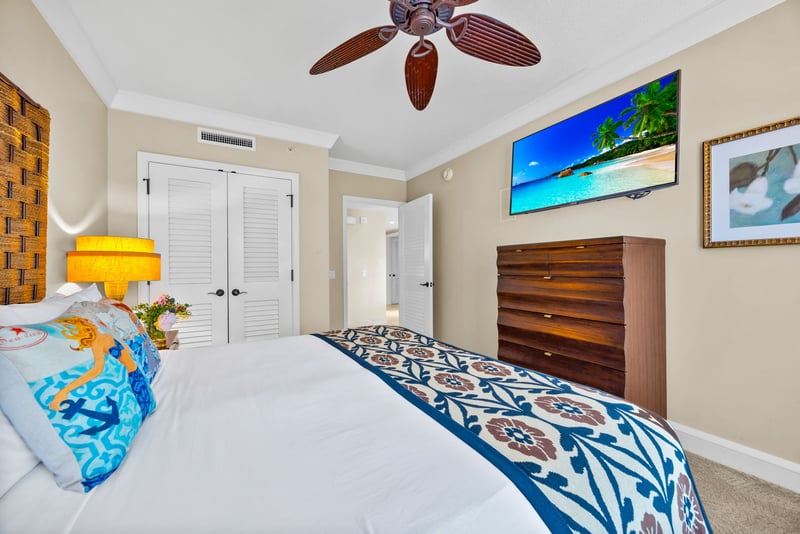 Primary bedroom features a plush King bed, 55" Smart TV, and peaceful garden views.