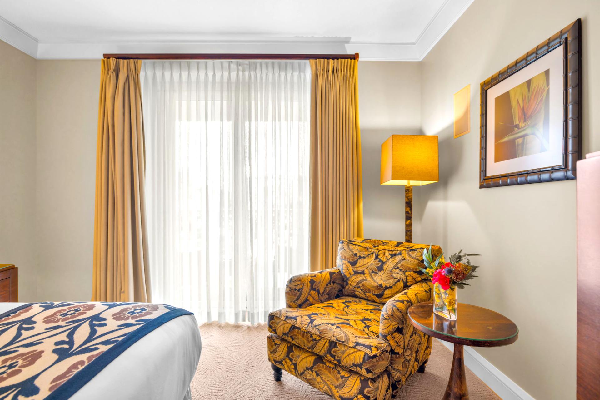 Peaceful guest bedroom with King bed, reading chair, and sliding doors to the lanai. HKH-203