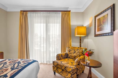 Peaceful guest bedroom with King bed, reading chair, and sliding doors to the lanai.