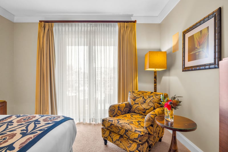 Peaceful guest bedroom with King bed, reading chair, and sliding doors to the lanai.