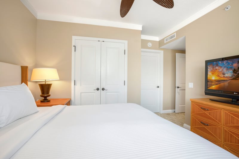 Relaxing bedroom with tropical charm, warm lighting, and double closets.
