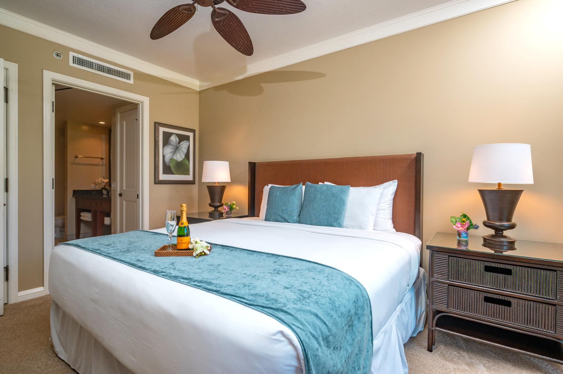 King bed with bedside lighting and dresser storage, steps from the ensuite bathroom.