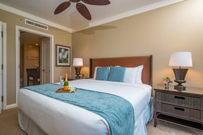King bed with bedside lighting and dresser storage, steps from the ensuite bathroom.