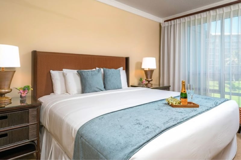 Primary bedroom with King bed and lanai access, plus soft natural light and tropical views.