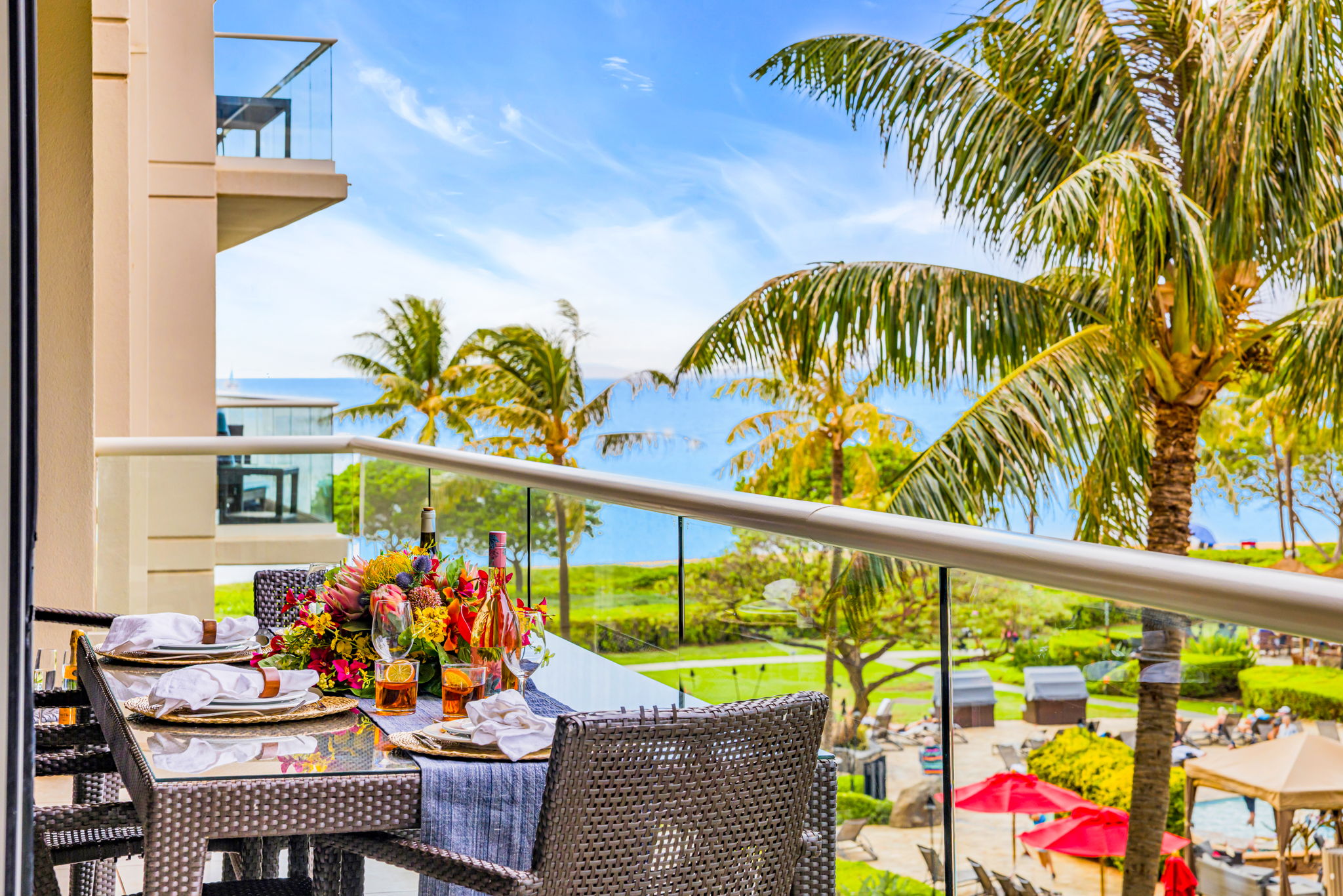 Lanai with vibrant tropical landscaping and peekaboo ocean views just beyond the palms. HKH-305