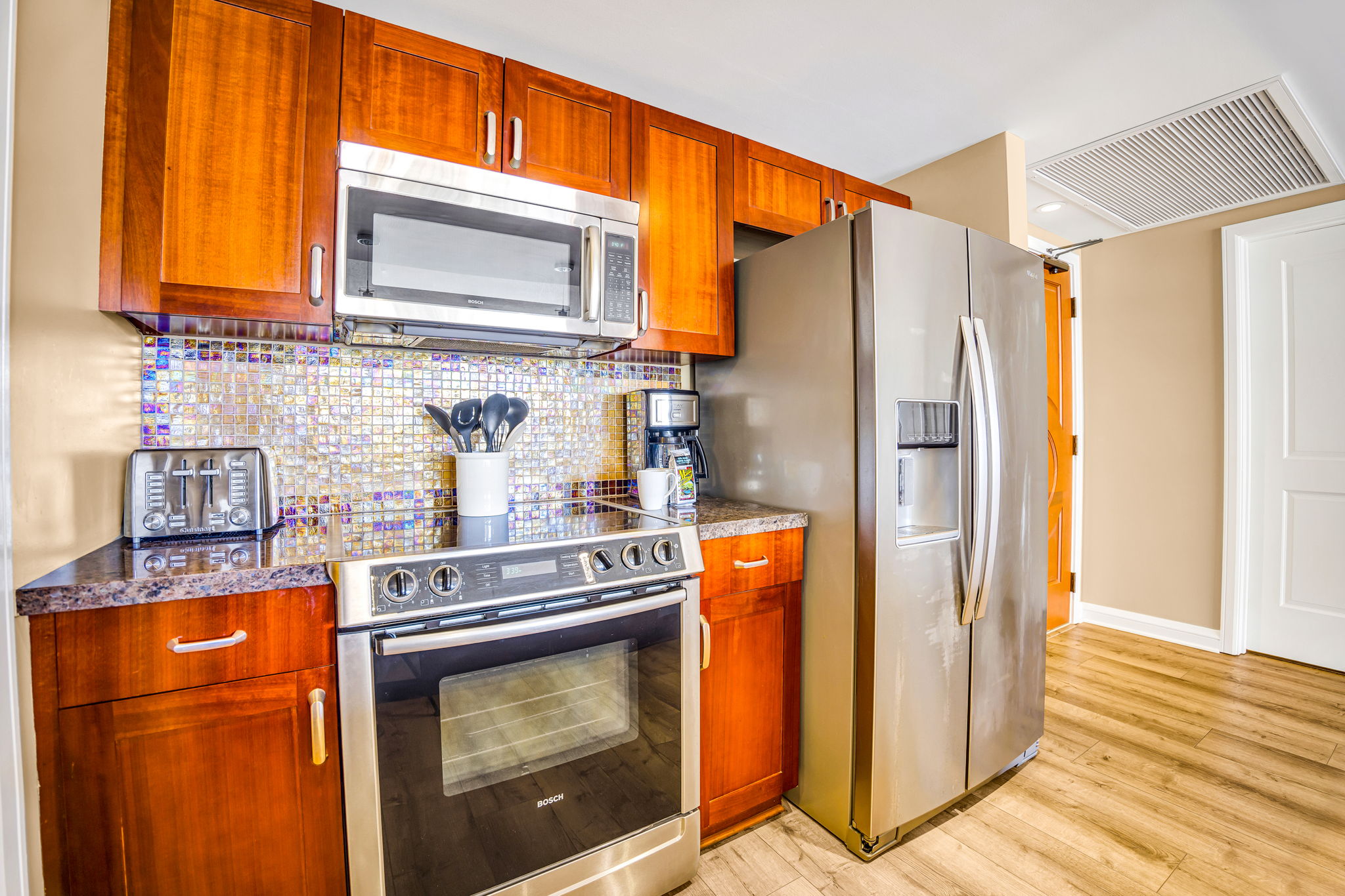 Modern kitchen with stainless steel appliances and wood cabinetry offers style and function for your stay. HKH-305
