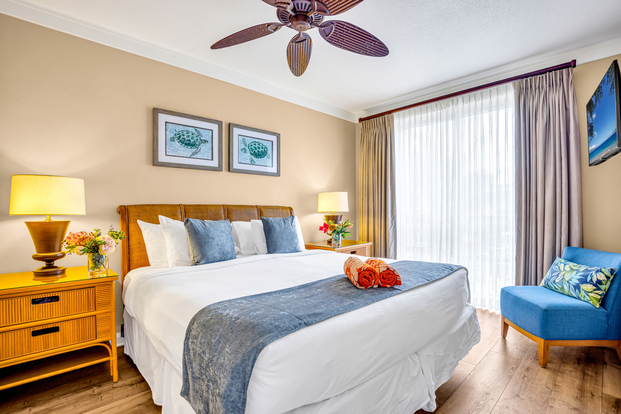King bed, ceiling fan, and warm wood tones create a serene primary suite with private lanai access. HKH-305