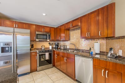 Fully equipped kitchen with sleek finishes, breakfast bar, and open flow into living and dining spaces