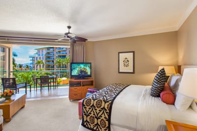 Spacious bedroom with direct lanai access, tropical views, and cozy seating for morning coffee or evening TV
