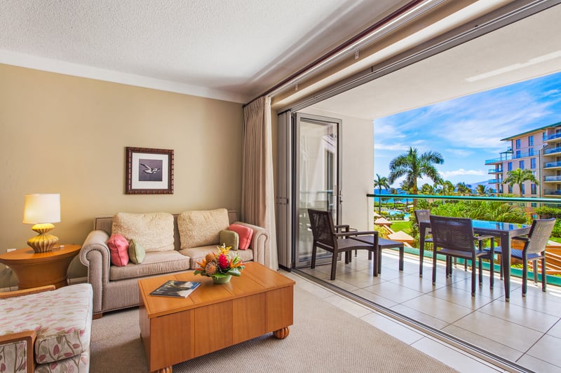 Elevated view of palm-fringed pools, thatched cabanas, and endless blue sea from your private balcony