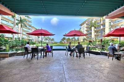 Enjoy coffee, breakfast, or cocktails at the open-air café with ocean views and shaded red umbrella seating HKH-423