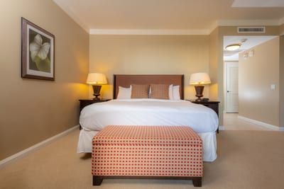 Elegant bedroom with king bed, custom headboard, and soft lighting that flows into an open kitchenette layout HKH-423