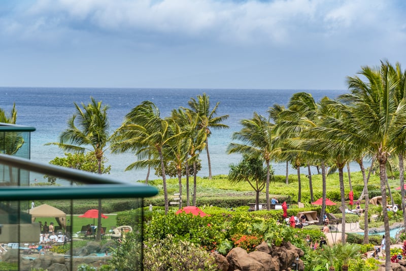 Enjoy elevated views of the Honua Kai Resort's lush tropical landscape, winding paths, and the Maui coastline beyond