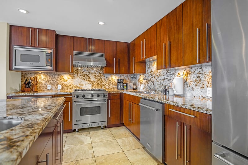 Kitchen detail shot highlights stainless appliances and stone finishes with practical design.