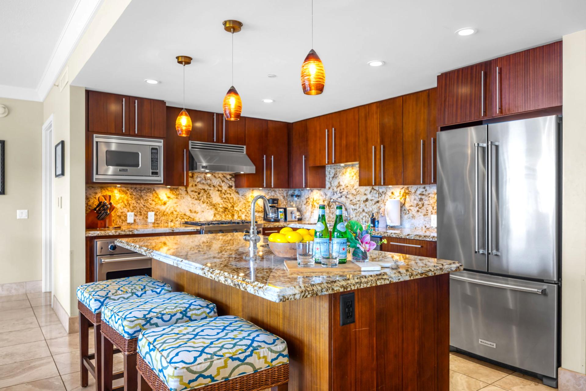 Fully equipped kitchen with stainless steel appliances and island bar for added prep space.