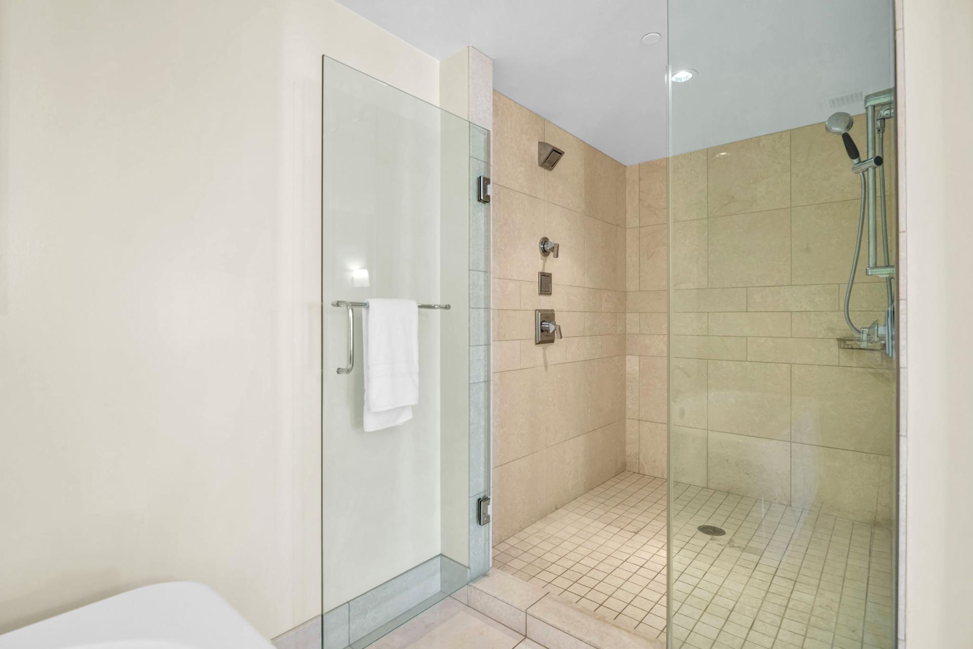 Walk-in shower with tile surround and glass door in guest bathroom.