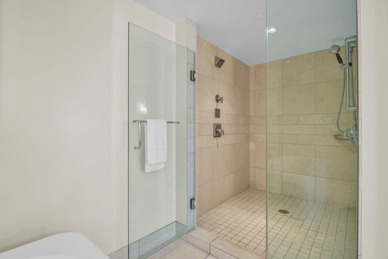 Walk-in shower with tile surround and glass door in guest bathroom.