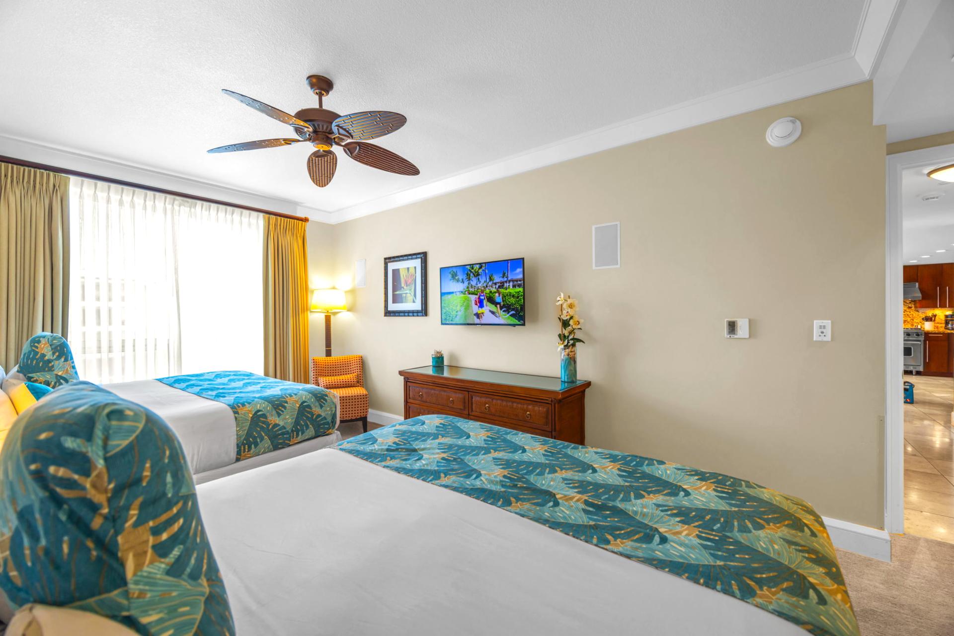 Guest bedroom with two King beds, ceiling fan, and tasteful island-inspired decor.