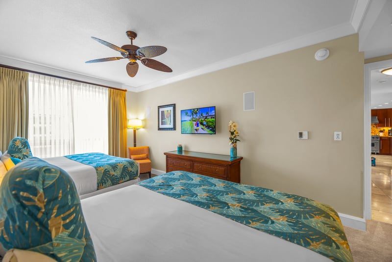 Guest bedroom with two King beds, ceiling fan, and tasteful island-inspired decor.