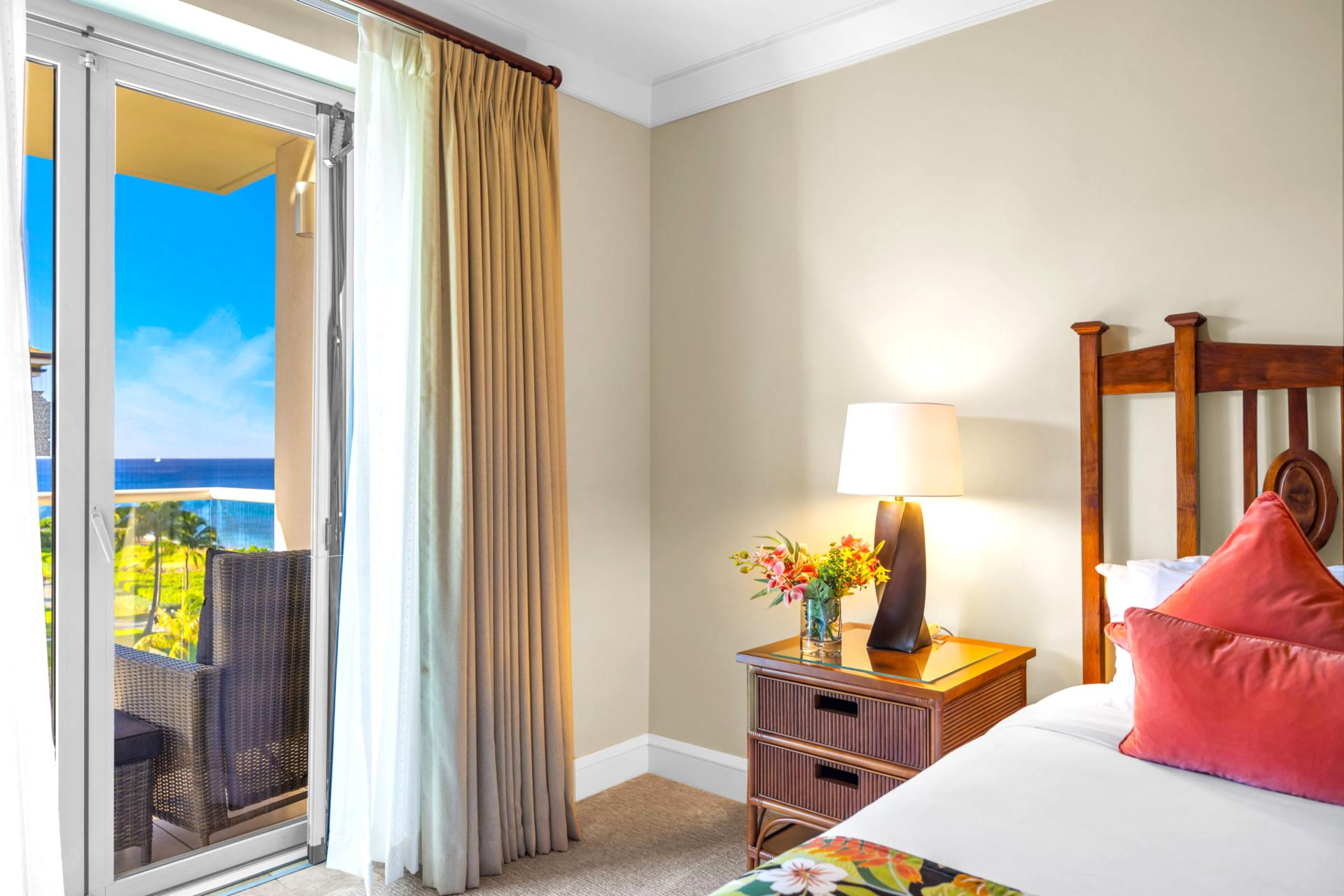 Primary bedroom with warm wood accents, King bed, and sliding door to the ocean-facing lanai.