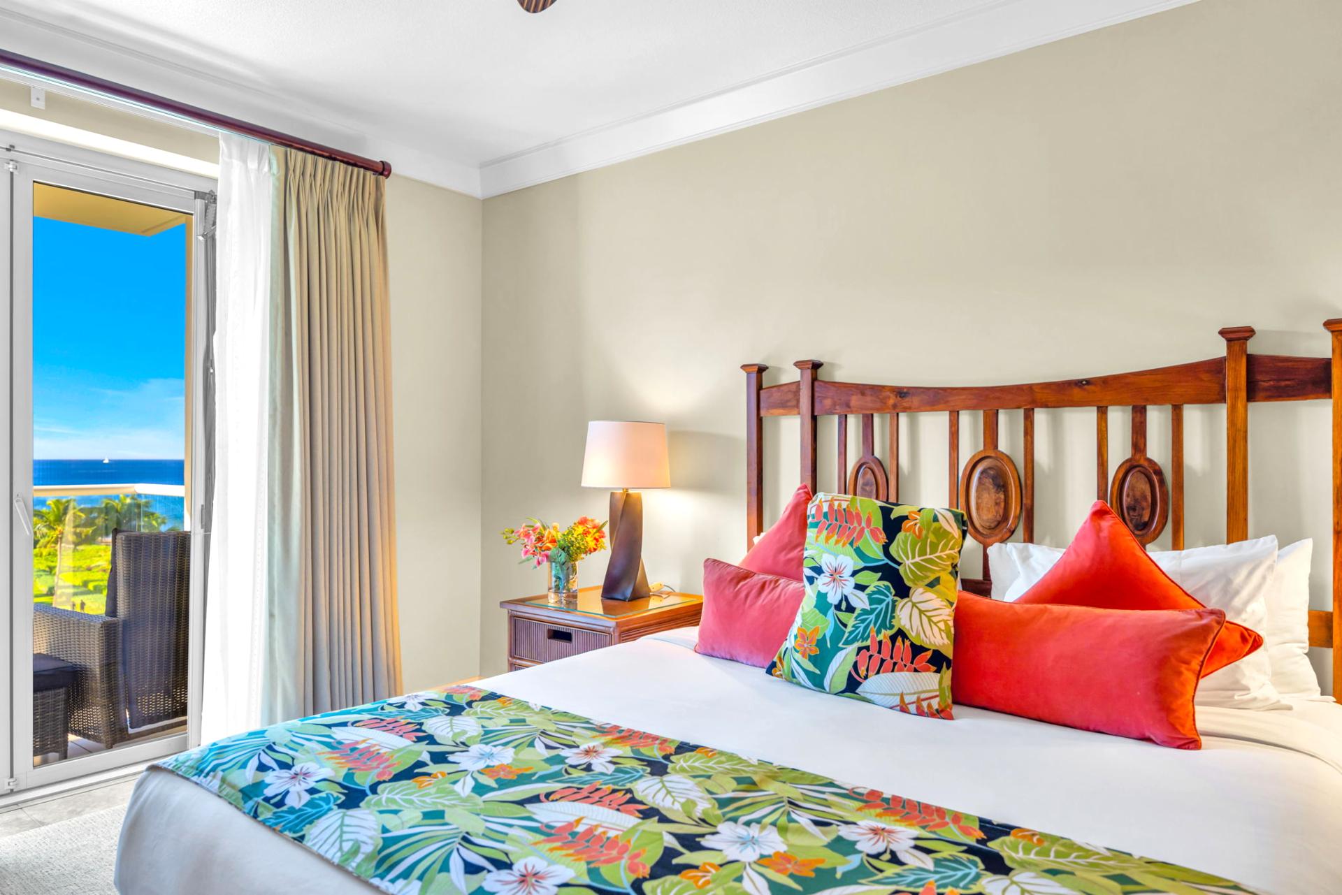 King bed with plush linens, ocean-view lanai access, and natural light in the primary suite.