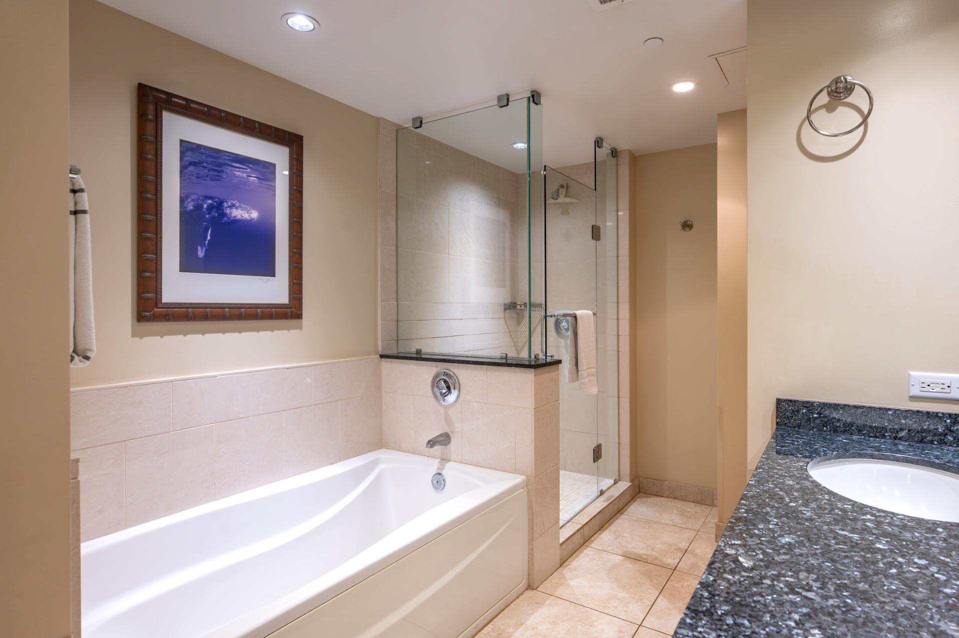 This guest bathroom features a granite vanity, soaking tub, and glass walk-in shower, perfect for relaxing after island adventures.