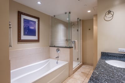This guest bathroom features a granite vanity, soaking tub, and glass walk-in shower, perfect for relaxing after island adventures. HKH-520