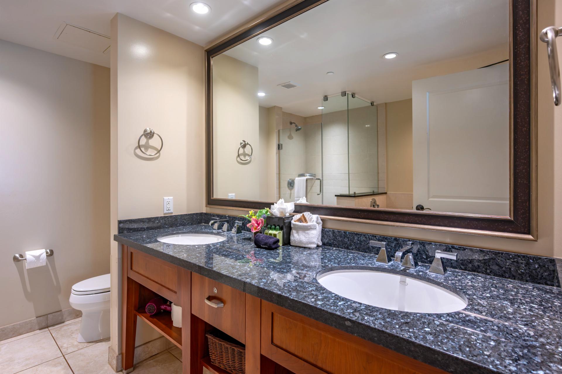The ensuite bath features a granite dual vanity, glass walk-in shower, and thoughtful amenities to refresh after a day in the sun.