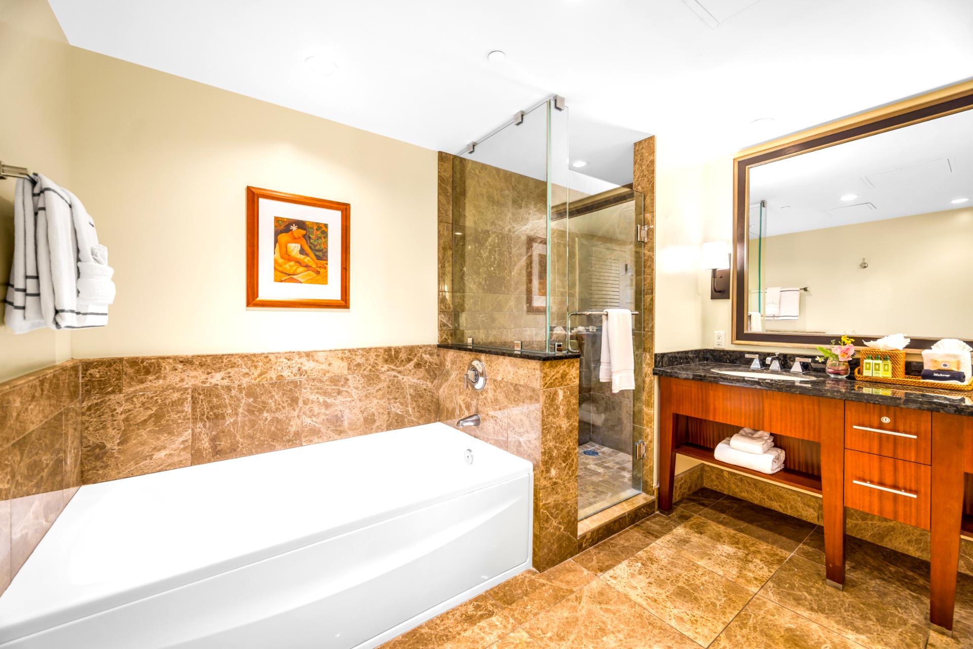 Refresh in the spacious primary bath featuring a soaking tub, granite vanity, and walk-in shower with rich tile surround.