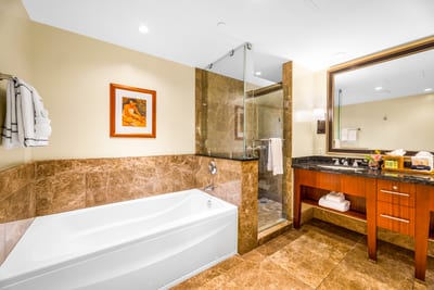 Refresh in the spacious primary bath featuring a soaking tub, granite vanity, and walk-in shower with rich tile surround. HKH-529