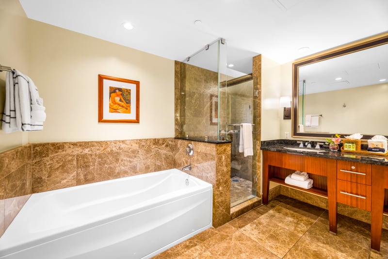 Refresh in the spacious primary bath featuring a soaking tub, granite vanity, and walk-in shower with rich tile surround. HKH-529