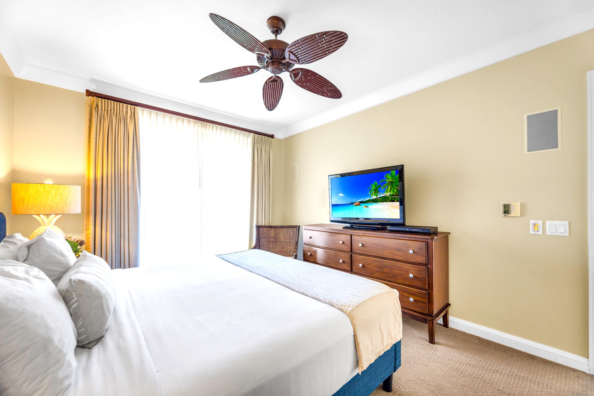 Wake up to natural light and your own private TV setup in this spacious primary suite with direct balcony access.