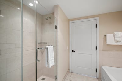 Spacious glass shower with soft tile tones and luxury towel detail. HKH-545