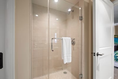 Glass-enclosed walk-in shower with sleek tiles and fresh white towel.