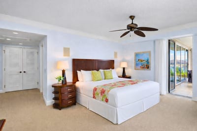 Primary suite with king bed, ocean-view terrace access, and calming coastal tones. HKH-550