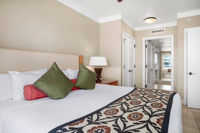 Guest bedroom with a king bed, designer pillows, and a hallway leading to the ensuite bathroom and closet. HKH-609