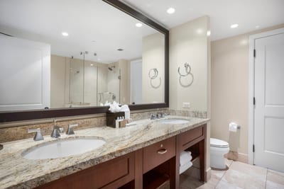 Spa-style bathroom with glass shower, granite countertops, and elegant lighting.