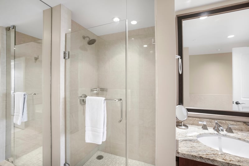Spacious walk-in shower with glass enclosure, rainfall head, luxury touches.