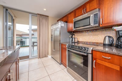 Gourmet kitchen with stainless appliances, mosaic backsplash, and balcony access.