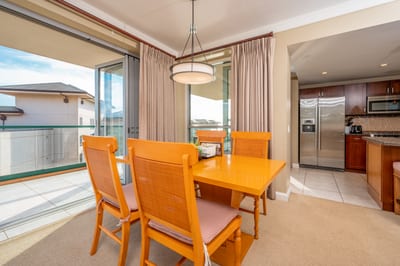 Sunlit dining space with open lanai and modern kitchen access.