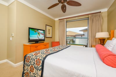 Cozy bedroom retreat with balcony access and tropical TV scene.