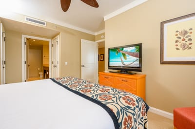 Tropical-themed bedroom with ensuite bath and relaxing coastal TV ambiance.