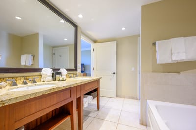 Elegant ensuite bathroom with double vanity, granite counters, and relaxing tub.