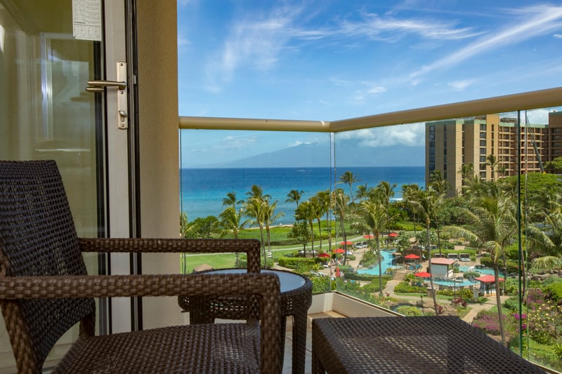 Relaxing balcony retreat with panoramic ocean and resort garden views.