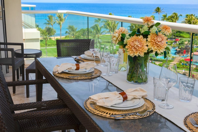 Chic oceanfront dining setup with fresh flowers and scenic views.