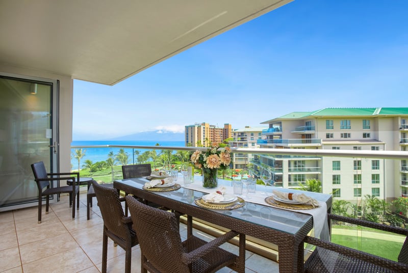 Stylish balcony dining with ocean views and modern resort buildings.