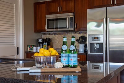 Granite island with refreshing setup, lemons, glasses, and sparkling water.