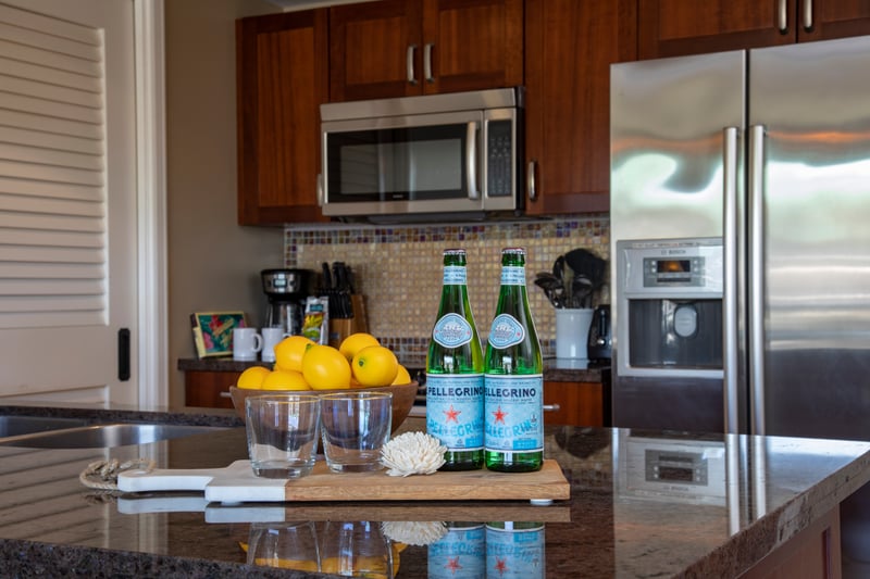 Granite island with refreshing setup, lemons, glasses, and sparkling water.